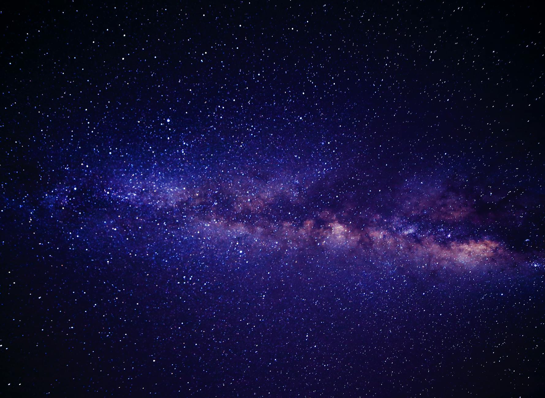 Milky Way galaxy arching over a dark landscape — the vast cosmic neighborhood containing Kepler-442b